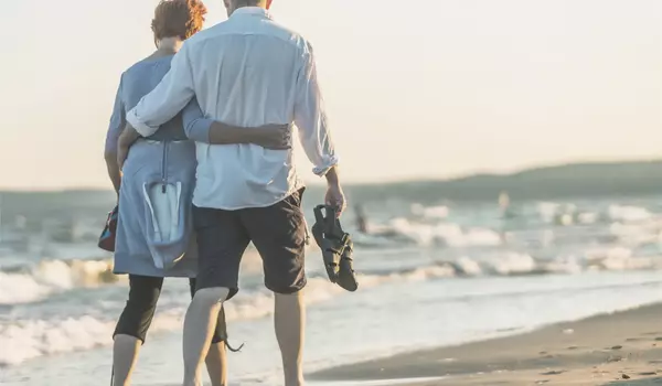 Zwei Personen die Arm in Arm am Strand laufen 