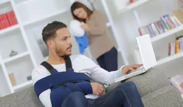 Mann mit Armschlinge sitzt am PC